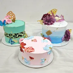 A collection of modern buttercream cakes made by a student. The class covers techniques like creating a leopard print fault line effect, watercolor blending, and palette knife painting with florals.