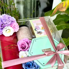The "Pastel Delight" acrylic box hamper is perfect for luxury gifting. It includes a reed diffuser, a Marks & Spencer photo frame, a Bath & Body Works candle, and treats from Theobroma.