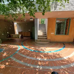 The morning terrace is an extension of the living space, with a floor pattern of terracotta and blue tiles that flows from inside to out. It is a space designed for slow mornings, shaded by the leaves of the surrounding trees.