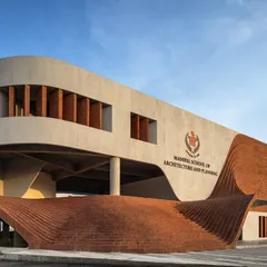 The facade of the Manipal School of Architecture and Planning features a fluid, wave-like brick structure that rises from the ground. This element serves as both an entrance and an informal amphitheater, creating a democratic space that is open and inviting.