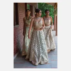 A group shot of three models walking in a line, showcasing a collection of pastel-colored lehengas by Vandana Sethi. This image is effective for lookbooks and campaigns that need to display multiple pieces from a collection.