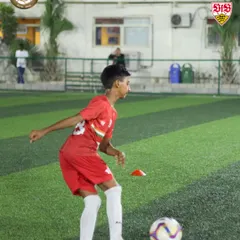 A young player in full concentration, maneuvering the ball during a drill. This focus is what we instill in our players. It's about being present and giving 100% in every moment of training.