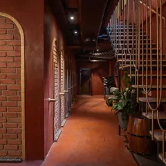 The corridor at 'Chambal' uses repetition in the arched brick doorways and the sleek staircase railing to create a strong sense of rhythm and direction, guiding patrons through the space.