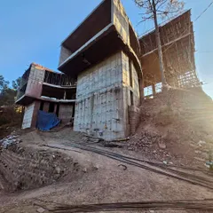 An upward-looking shot of the cantilevered structure, emphasizing its dramatic projection out from the hillside. This perspective showcases the ambitious structural design and the creation of floating architectural forms.