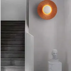 This pleated sunburst wall sconce adds a beautiful texture and a warm halo of light, shown here elevating a simple hallway.