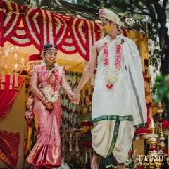 Hand in hand, the newlyweds embark on their journey of forever. This photo captures them walking down the aisle, surrounded by enchanting floral decor that perfectly complements their traditional South Indian wedding attire.