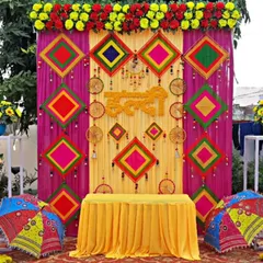 Here is a vibrant Haldi ceremony backdrop, bursting with color. I used traditional elements like Rajasthani umbrellas, colorful kite-shaped hangings, and a mix of real and artificial flowers to create a truly festive atmosphere for this outdoor event.