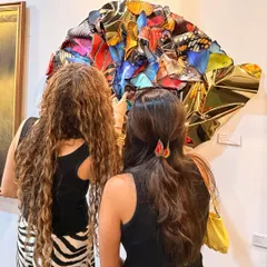 Two visitors admiring "Wings of Resilience" at an art gallery, drawn in by the vibrant colors and complex form.