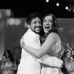A black and white shot capturing the pure, uninhibited laughter of a couple on their sangeet night. This is what true celebration looks like.