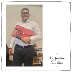 A great gift for our patron Meghana's husband. He's holding the Big Jude folio clutch, customized with a vibrant Gond art motif on Cranberry red leather. It's a bold and artistic statement piece.