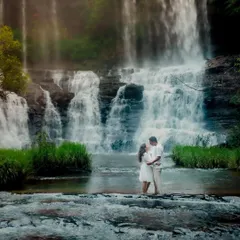 A breathtaking wide shot of the couple standing before a massive, multi-tiered waterfall. This photo captures the scale of nature and the intimacy of their connection within it.