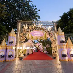 The grand entrance to Varnnika's fairyland, with a red carpet leading through a magnificent floral archway flanked by purple and gold castle turrets.
