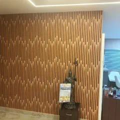 This accent wall features fluted panels arranged in a dynamic, geometric pattern. The wood finish brings warmth, while the clean vertical lines and integrated LED strip lighting create a modern and sophisticated look.