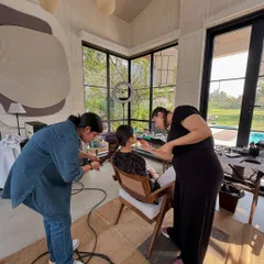 The dream team in action. This behind the scenes shot shows the collaborative effort of a campaign shoot, with hair and makeup artists working together to perfect the look before the camera rolls.