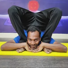 Another view of the challenging Yoganidrasana, showcasing the practitioner's calm focus and extreme flexibility.