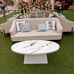 A modern and luxurious seating arrangement with beige sofas, printed cushions, and a white marble-topped coffee table, perfect for a chic outdoor lounge.