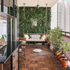 This spacious balcony is designed for relaxation, featuring a comfortable swing, a vertical garden, and numerous potted plants. The wooden deck flooring adds a warm, natural touch.
