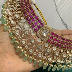A detailed hand-held view of the premium ruby and mint bridal choker, showcasing the quality of the stones and the intricate setting.