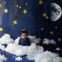 A wide shot of our "dreamland" theme, with a baby sleeping peacefully on a cloud under a starry night sky with a big, bright moon.