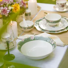 An elegant outdoor dining scene set with Vigneto's floral crockery. The soft, natural light, fresh flowers, and lit candles create a dreamy and romantic atmosphere for a special meal.