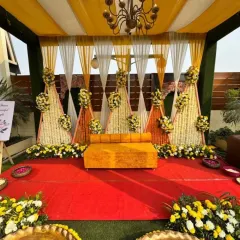 This outdoor Haldi stage combines traditional elements with a clean, contemporary design. Yellow and white drapes frame a backdrop of floral cones, creating a bright and cheerful space for the ceremony.