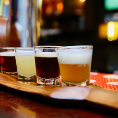 A beer flight, perfect for showing variety. This close-up shot highlights the different colors and textures of four distinct craft beers, inviting customers to try a tasting platter.