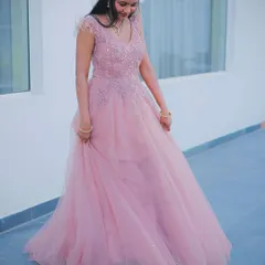 This soft pink ball gown is pure elegance. The bodice is delicately embroidered, and the shoulders have a touch of feather detailing, flowing into a multi-layered tulle skirt that's perfect for a fairytale moment.