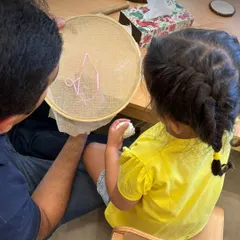 A parent and child work together on an embroidery project. These shared activities strengthen bonds and create opportunities for connection, modeling the patience and collaboration we hope to foster in children.