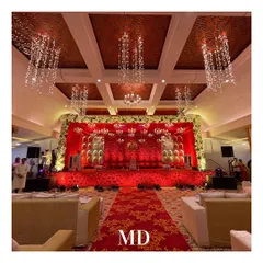 The main stage for a red-themed engagement. The backdrop is a wall of red flowers with alcove details, and the ceiling is adorned with cascading crystal chandeliers, creating a luxurious and romantic atmosphere.