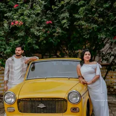 A cool, stylish pose with a couple leaning against a vintage yellow car, surrounded by greenery.