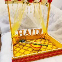 The Haldi ceremony is all about joy and vibrant colours. This canopy-style platter is one of my most-loved designs, bringing a festive and traditional feel. It comes with a matching bowl for the haldi paste and is decorated with beautiful artificial flowers and pearls.