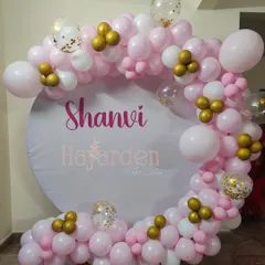 A simple and sweet circular backdrop with a custom name and a partial balloon garland in pink and white.