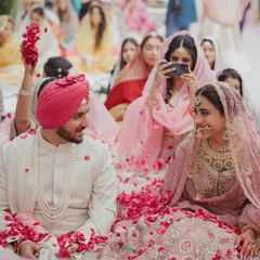 A beautiful moment from an Anand Karaj ceremony, with the couple seated amidst a shower of rose petals, sharing a look of love and understanding.