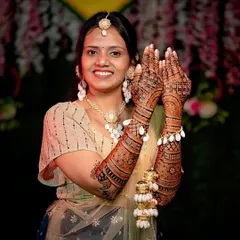 A happy bride showing off her mehandi stain. The design features a mix of geometric and floral patterns, and the rich color demonstrates the quality of the henna used.