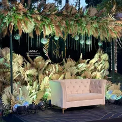 A chic and rustic Sangeet stage, featuring a backdrop of dried pampas grass, a custom monogram, and hanging disco balls for a touch of glam.