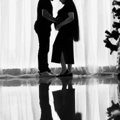 A dramatic black and white silhouette of a couple sharing an intimate moment. The reflection on the floor adds a beautiful symmetry, making this a truly artistic shot.