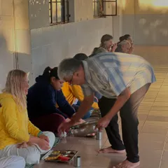 Karma Yoga, or selfless service, is a cornerstone of our training. Here, a student serves food to his peers, an act of humility and love.