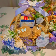 A beautifully curated thank you basket for baby shower guests. This one features chocolates, small gifts, and is decorated with a lavender ribbon and floral accents to match the event's color palette. A perfect 'shukriya' for your loved ones.