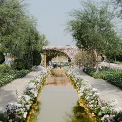A mirrored aisle reflects the sky, leading to a stunning pastel floral mandap. We designed this walkway at Suryagarh to create a dramatic and ethereal entrance for the bride, making her journey to the ceremony feel like walking on water.