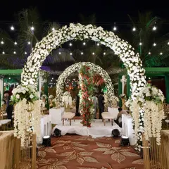 An elegant evening reception under the stars. The series of white floral arches creates a dreamy, romantic pathway, while the warm lighting adds a touch of magic, proving that luxury is a feeling, not just a look.