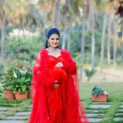 A full-length view of the stunning red velvet and tulle robe combination. This outfit is designed to make a statement in a beautiful garden or estate setting for your maternity photoshoot.