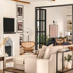 A view of the family room, centered around the custom Spanish-style fireplace. A large sectional sofa provides plenty of seating for movie nights, while the gallery wall of family photos makes the space feel deeply personal.
