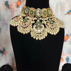 Embrace tradition with this beautiful Chand Kundan jewelry. The combination of green enamel, uncut stones, and pearl clusters gives it a classic yet fresh feel.