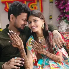 A lovely couple posing together at their mehandi ceremony, with the bride showcasing her intricate henna and the groom with a simple design.