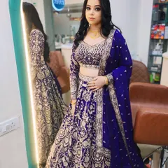 A full-length shot of a client ready for a wedding party. Her royal blue and silver lehenga is complemented by a bold eye and a soft wavy hairstyle.
