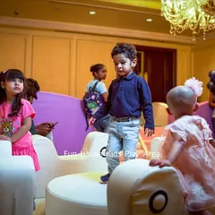 Toddlers exploring the white merry-go-round at an indoor party. Our equipment is designed to be safe and accessible for the littlest guests.