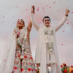 The triumphant moment right after the jaimala. The couple's raised hands and joyful smiles, framed by a shower of petals, create a perfect picture of celebration.