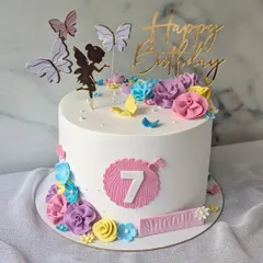 A pretty floral and fairy cake for a 7th birthday. The design features a fairy silhouette, colorful flowers, and delicate butterflies.