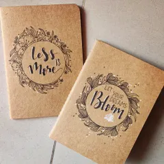 These pocket-sized journals feature kraft paper covers with hand-drawn floral wreaths and motivational quotes like 'Less is More' and 'Let Your Dreams Bloom'. They are perfect for jotting down thoughts on the go.