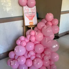 A simple yet beautiful welcome stand for a butterfly-themed party, with a custom sign and an arrangement of pink balloons with butterfly stickers.